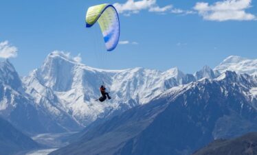 Traveler enjoying paragliding in North Pakistan above lush valleys during a thrilling northern Pakistan tour adventure