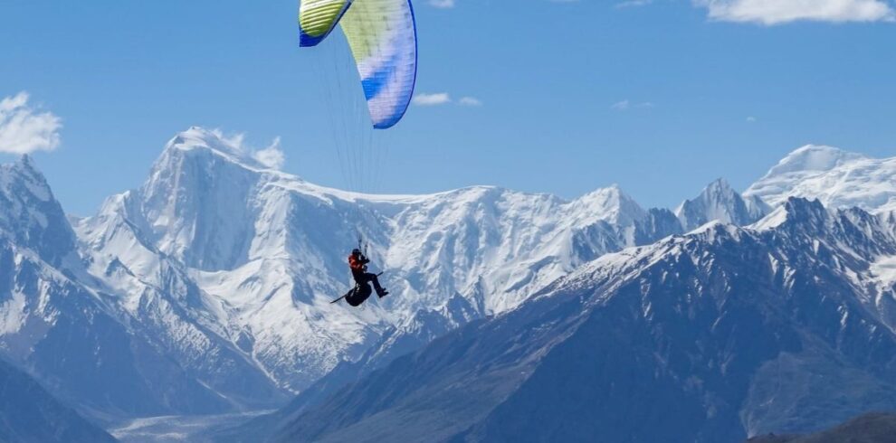 Traveler enjoying paragliding in North Pakistan above lush valleys during a thrilling northern Pakistan tour adventure