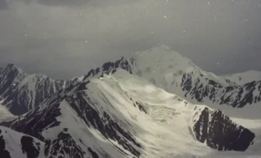 Mountaineer ascending a snowy ridge in Khunjerab Pass, surrounded by Karakoram peaks